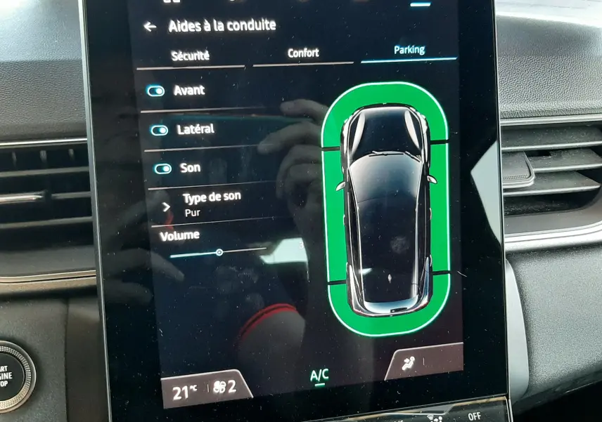 Écran tactile intérieur du Renault Captur II gris Cassiopée montrant l'aide au stationnement avec vue du dessus du véhicule.