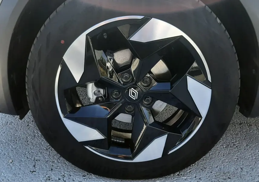 Gros plan sur la roue avant droite d’un Renault Captur gris Cassiopée, jante alliage noire et argentée au design géométrique.