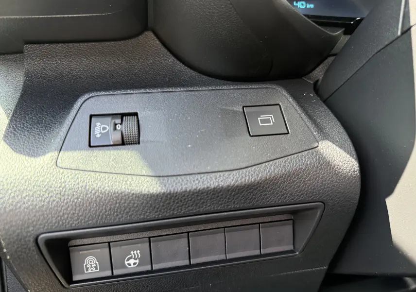 Vue rapprochée du tableau de bord côté gauche du Citroën Berlingo gris, avec commandes de réglage des phares et boutons fonctionnels.