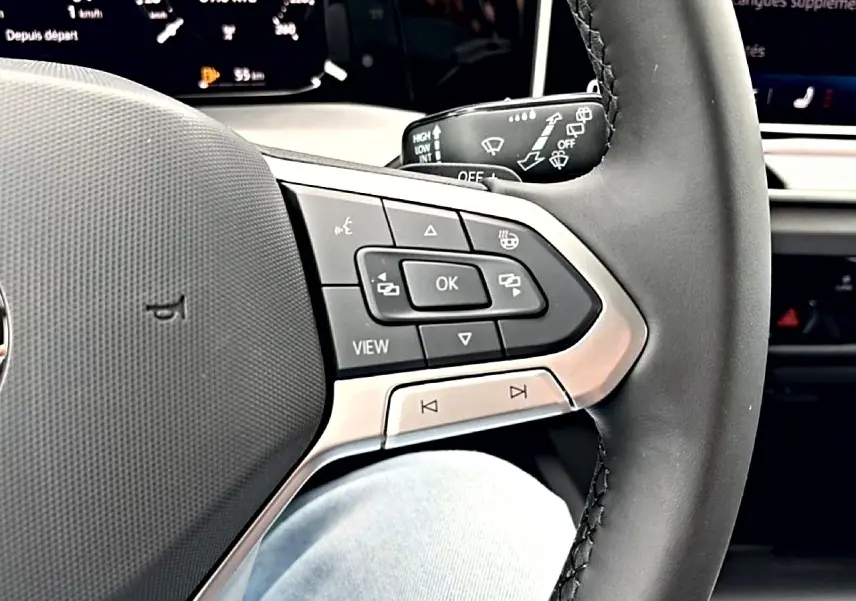 Gros plan sur le volant noir de la Volkswagen Golf 2026, montrant les commandes multifonctions côté gauche.