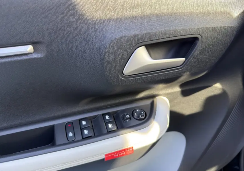 Gros plan sur la porte intérieure côté conducteur de la Citroën C3 noire, avec commandes des vitres et poignée argentée.