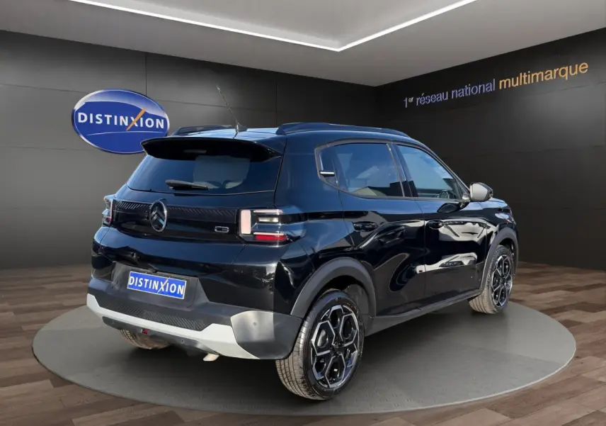 Vue 3/4 arrière droite d'une Citroën C3 Turbo 100 BVM6 MAX noire avec jantes noires et toit noir en showroom.