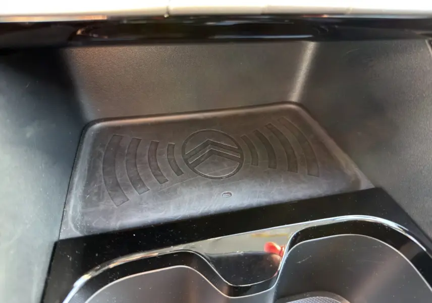 Gros plan sur la zone de recharge par induction avec logo Citroën embossé, intérieur noir brillant de la C3 Turbo 2025.