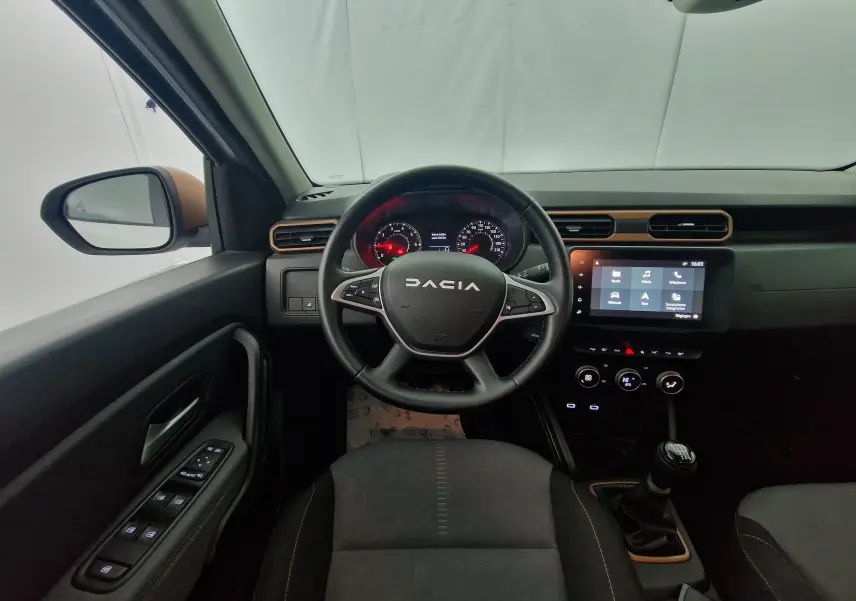 Vue intérieure centrée sur le volant noir DACIA et le tableau de bord avec écran tactile du Duster blanc 2024.
