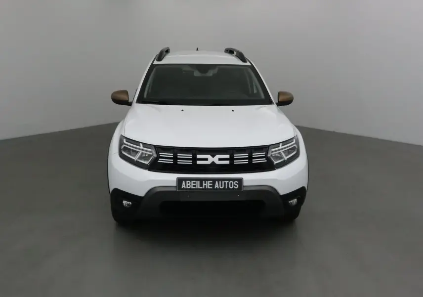 Vue frontale d'un Dacia Duster blanc 2024 avec rétroviseurs bronze et calandre noire distinctive.