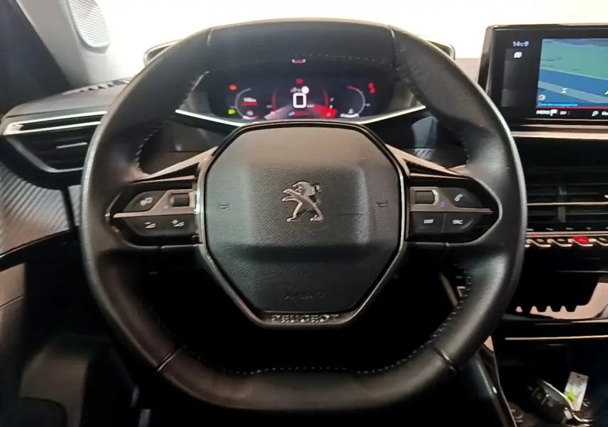 Volant cuir noir de Peugeot 2008 PureTech 130 2021 avec commandes intégrées et tableau de bord numérique en arrière-plan.