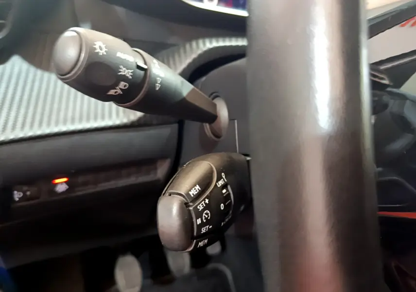 Gros plan sur les commandes au volant noir du Peugeot 2008 gris clair, mettant en valeur les boutons de régulateur de vitesse.