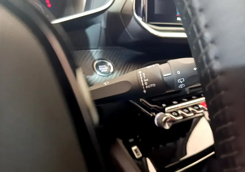 Gros plan sur la commande d'essuie-glace et bouton démarrage dans l'habitacle noir du Peugeot 2008 gris clair.