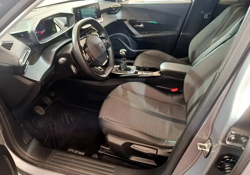 Intérieur avant droit du Peugeot 2008 gris clair 2021, volant cuir, tableau de bord numérique et boîte manuelle visible.