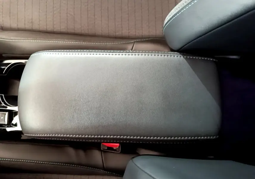 Vue rapprochée du couvercle de l'accoudoir central en cuir noir à surpiqûres dans l'habitacle du Peugeot 2008 gris clair.