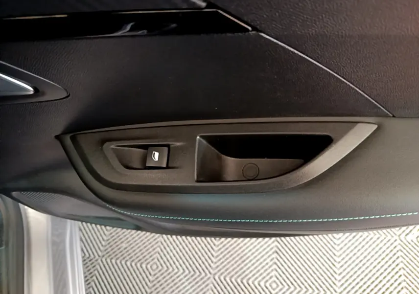 Détail de la poignée intérieure et commande de vitre côté gauche d'une Peugeot 2008 gris clair de 2021.