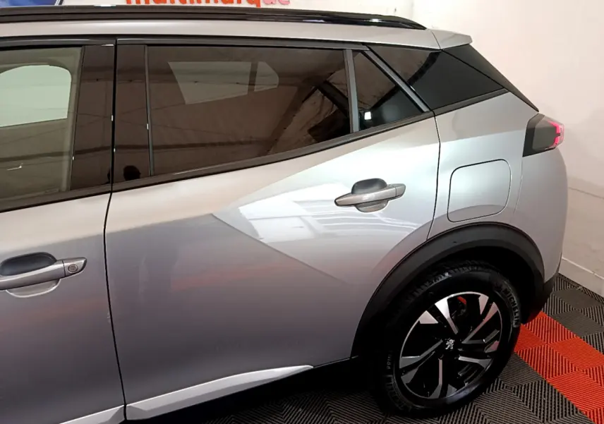 Vue latérale côté droit d'un Peugeot 2008 gris clair avec jantes noires et toit noir contrasté.