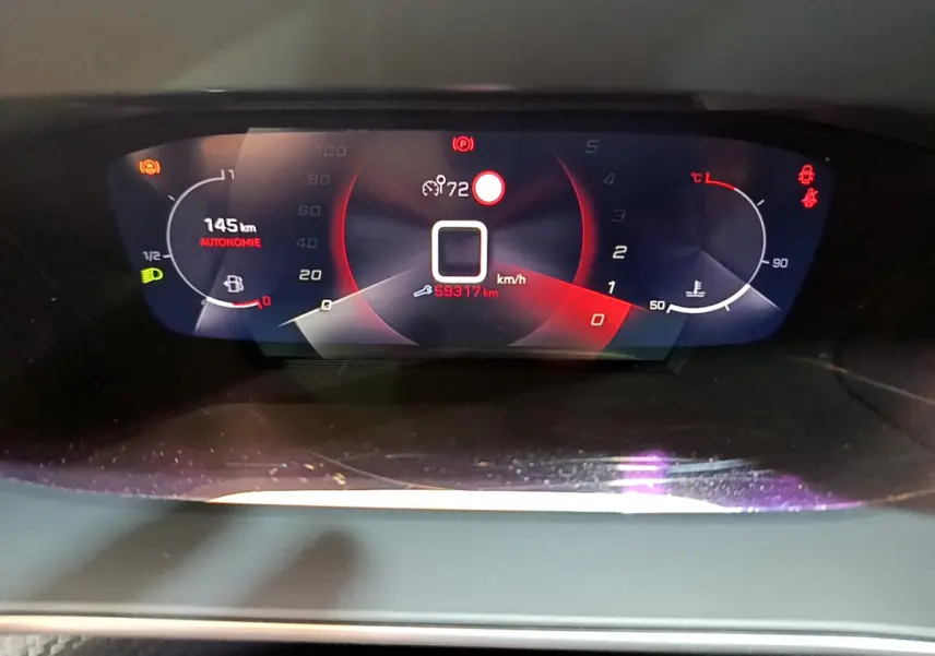 Vue rapprochée du tableau de bord numérique du Peugeot 2008 gris clair, affichant autonomie, vitesse et température moteur.