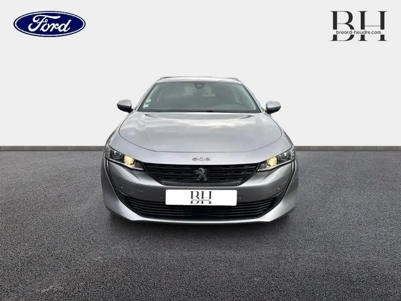 Vue avant d'une Peugeot 508 SW gris Platinium avec calandre noire et phares allumés sur fond neutre.