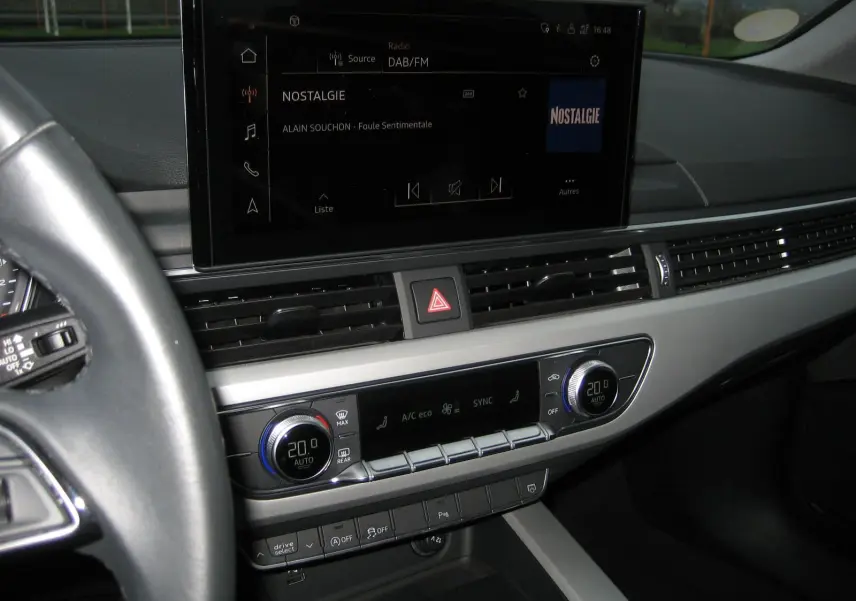 Vue intérieure du tableau de bord de l'Audi A4 Avant noir 2022, avec écran tactile et commandes climatisation digitales.