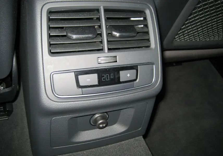 Vue rapprochée de la commande de climatisation arrière et prise 12V dans l'Audi A4 Avant noire 2022.