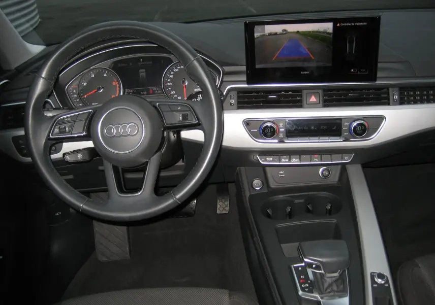 Intérieur de l'Audi A4 Avant noir, vue centrée sur le volant et le tableau de bord avec écran de caméra de recul.
