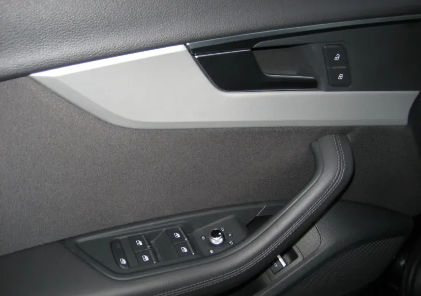 Gros plan sur la porte intérieure côté conducteur de l'Audi A4 Avant noire, montrant les commandes de vitres et de verrouillage.