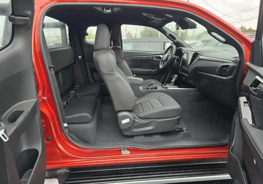Intérieur côté droit du pick-up Isuzu D-MAX orange métal 2025, sièges en cuir noir et tableau de bord moderne.