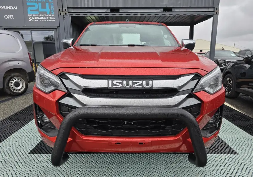 Vue frontale d'un Isuzu D-MAX orange métallisé avec bullbar noir et calandre chromée sous la pluie.
