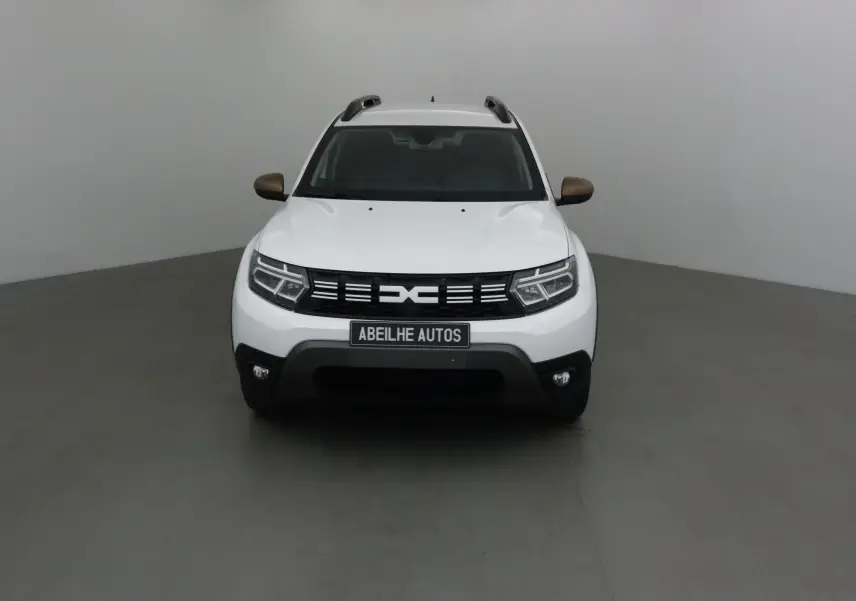 Vue frontale d'un Dacia Duster 4x4 blanc 2024 avec rétroviseurs bronze et calandre noire distinctive.