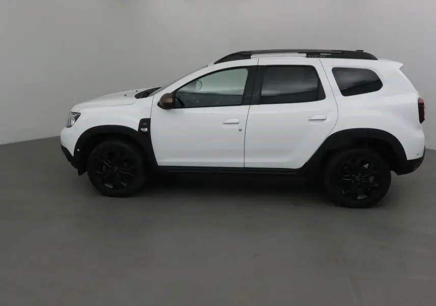 Profil côté gauche du Dacia Duster 4x4 blanc 2024 avec jantes noires et barres de toit noires marquées Duster.