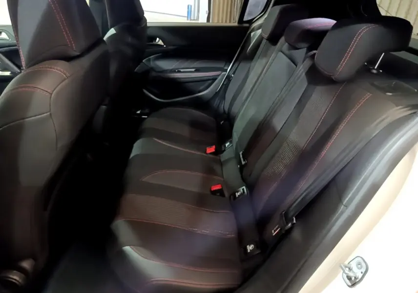 Vue intérieure côté droit des sièges arrière noirs avec surpiqûres rouges d'une Peugeot 308 GT Line blanche de 2019