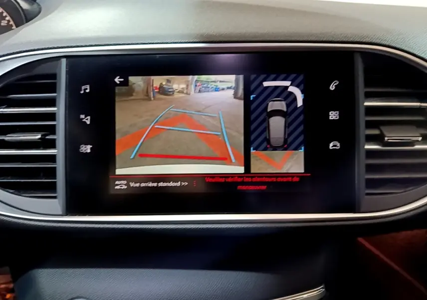 Écran tactile central de la Peugeot 308 GT Line blanc montrant l’aide au stationnement arrière avec caméra et capteurs.
