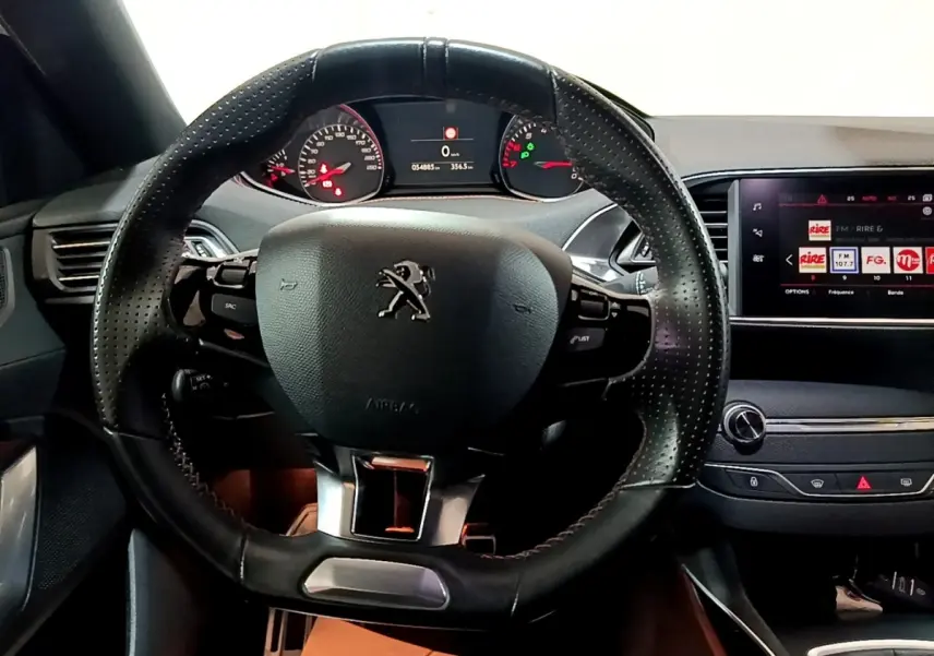 Vue intérieure centrée sur le volant cuir perforé et le tableau de bord numérique de la Peugeot 308 GT Line 2019.