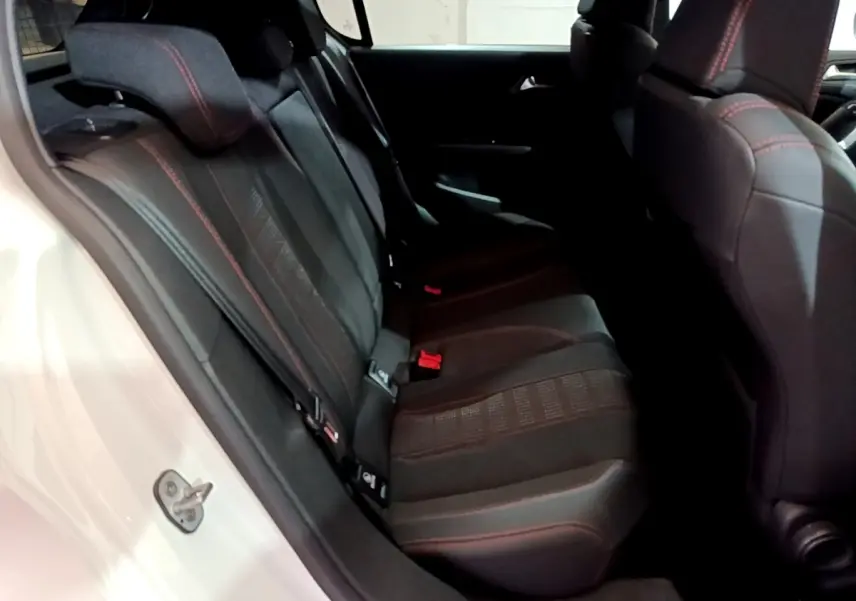 Vue côté gauche des sièges arrière noirs avec surpiqûres rouges d'une Peugeot 308 blanche de 2019.