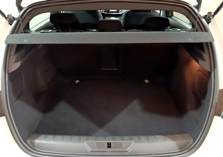 Coffre ouvert d'une Peugeot 308 blanche, vue arrière montrant l'espace de chargement vide et la tablette cache-bagages.