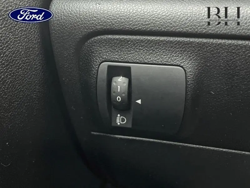 Gros plan sur le réglage de hauteur des phares dans l'habitacle noir d'une Renault Mégane Break gris platine.