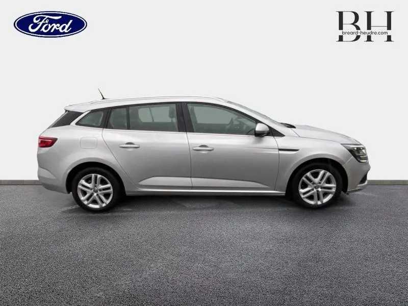 Profil droit d'une Renault Mégane Break 1.3 TCe 140ch gris platine, avec barres de toit et jantes alliage visibles.