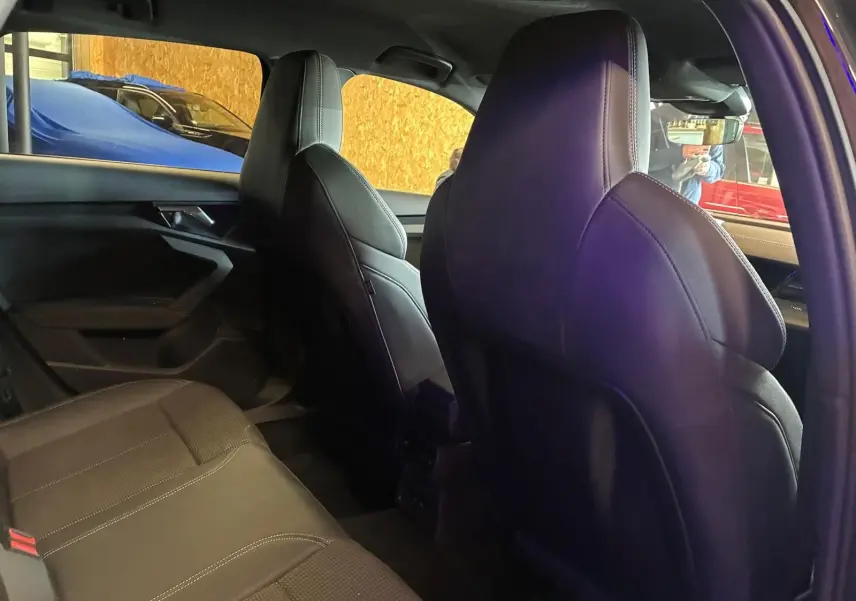 Vue intérieure arrière droite de l’Audi A3 Sportback 2023 noire, sièges sport en cuir et ciel de pavillon noir.