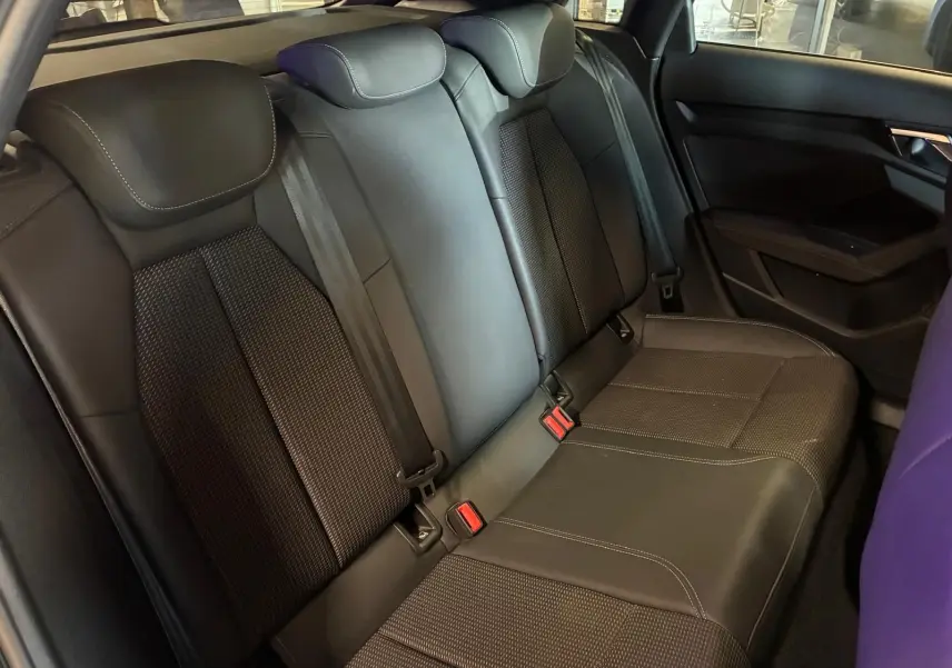 Vue intérieure du siège arrière noir de l'Audi A3 Sportback 2023 avec ceinture de sécurité et accoudoir central.