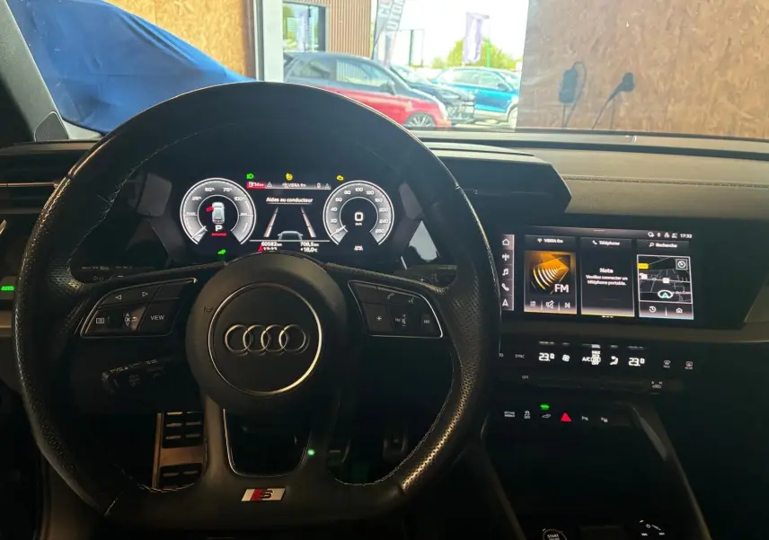 Vue intérieure centrée sur le volant cuir multifonctions S line et le tableau de bord numérique de l'Audi A3 Sportback 2023.