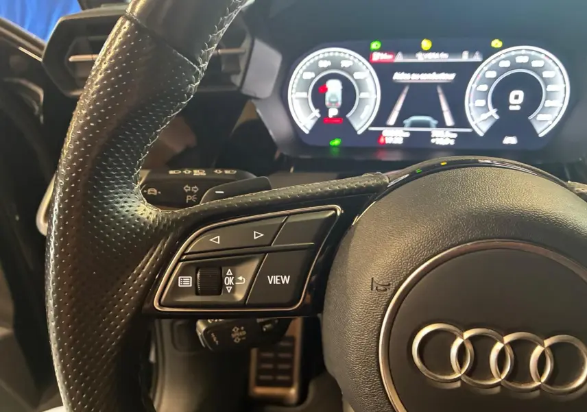 Gros plan sur le volant cuir multifonctions et le tableau de bord numérique éclairé de l'Audi A3 Sportback 2023.