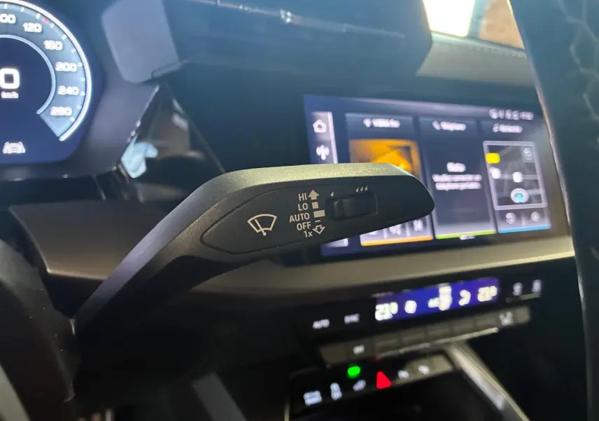 Gros plan sur la commande d’essuie-glace à gauche du volant dans l’habitacle noir de l’Audi A3 Sportback 2023.