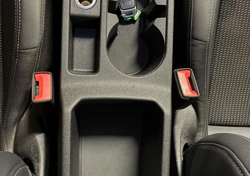 Vue plongeante sur la console centrale noire de l'Audi A3 Sportback avec clé et porte-gobelets intégrés.
