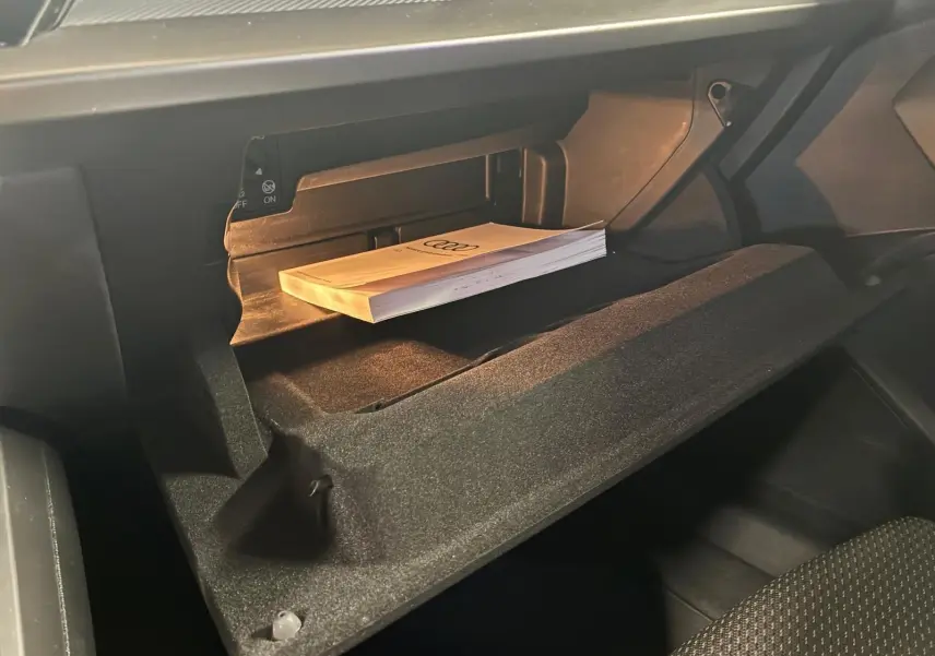 Gant de rangement ouvert côté passager avec manuel Audi posé à l'intérieur d'un Audi A3 Sportback noir 2023.