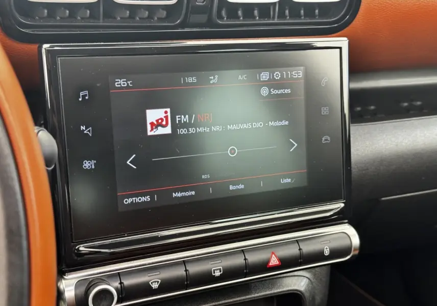 Écran tactile central de la Citroën C3 Aircross 2020, affichant la radio FM NRJ, avec tableau de bord noir et orange.