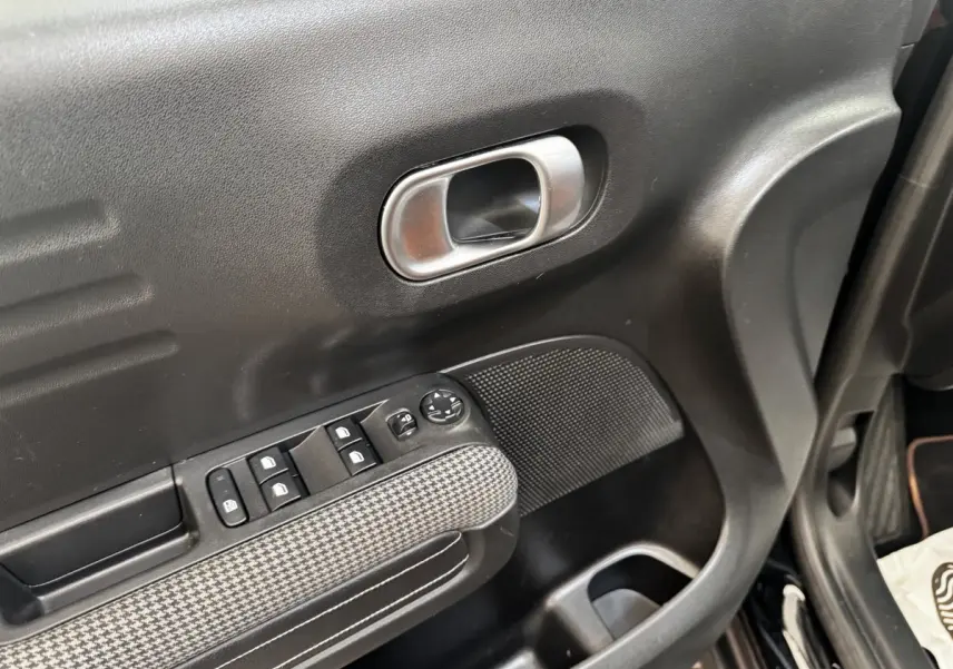 Gros plan sur la porte côté conducteur noire de la Citroën C3 Aircross 2020 avec commandes de vitres et poignée argentée.