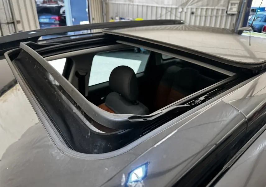Toit ouvrant panoramique ouvert sur le côté gauche d'une Citroën C3 Aircross noire, intérieur partiellement visible.