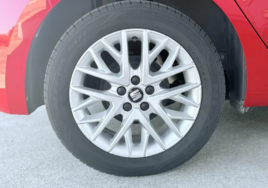 Gros plan sur la roue avant droite d'une SEAT Ibiza rouge passion, avec jante alliage argentée au design fin et moderne.