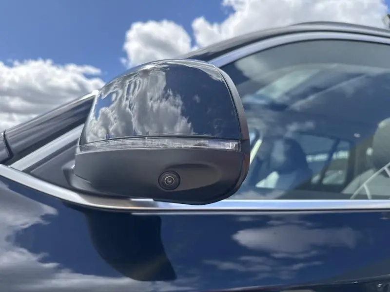 Rétroviseur côté gauche noir brillant avec caméra intégrée sur BMW X3 xDrive30e Saphirschwarz métallisé.