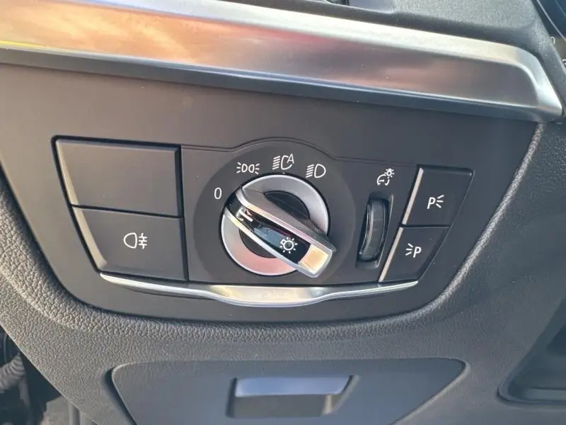 Gros plan sur le sélecteur de phares noir et chrome du BMW X3 xDrive30e 2023, tableau de bord intérieur côté gauche.