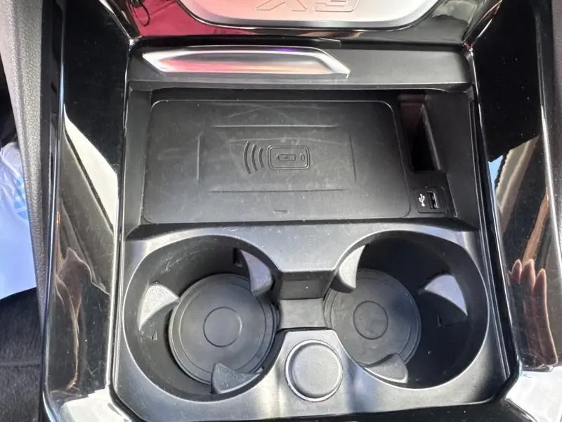 Gros plan sur la console centrale noire du BMW X3 xDrive30e 2023 avec porte-gobelets et chargeur sans fil.
