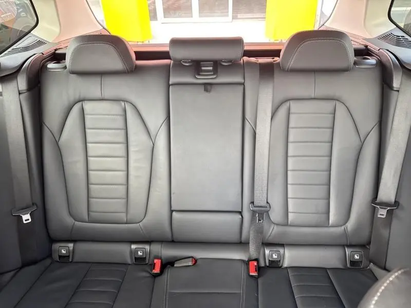 Vue intérieure arrière des sièges en cuir noir du BMW X3 xDrive30e 2023 avec appuie-têtes et ceintures de sécurité visibles.