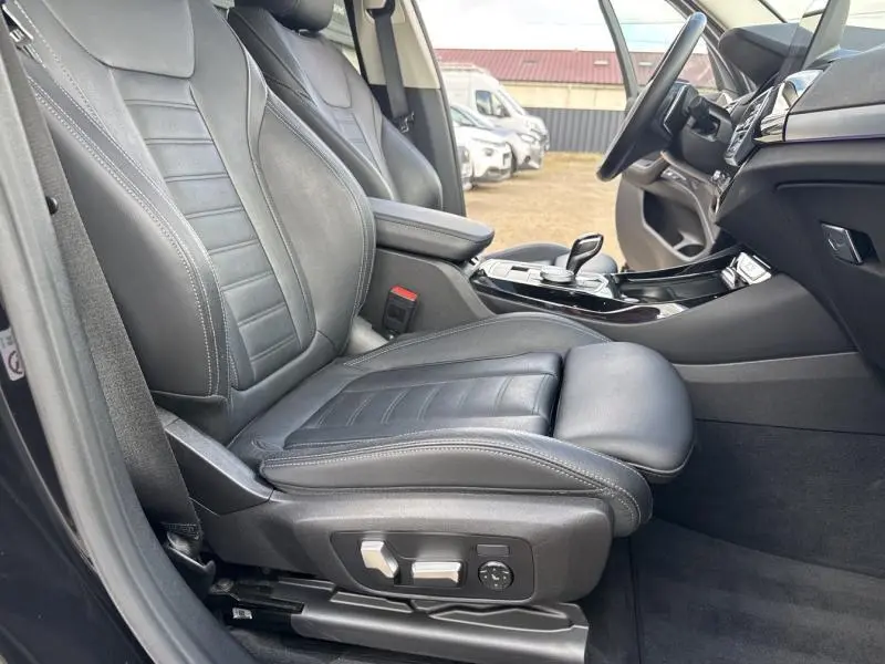 Vue intérieure côté conducteur de la BMW X3 xDrive30e 2023 avec sièges sport en cuir noir et console centrale moderne.