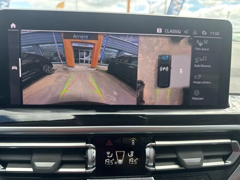 Affichage écran intérieur montrant la caméra de recul et l'assistance au stationnement du BMW X3 xDrive30e noir saphir.
